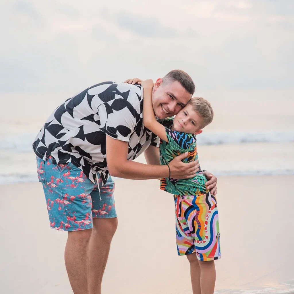 father and son huging each other on beach smiling